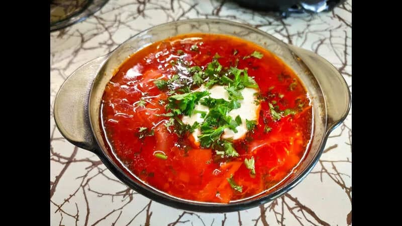 Борщ по-болгарски: светлый прозрачный суп с фрикадельками, зеленью и долькой лимона в тарелке
