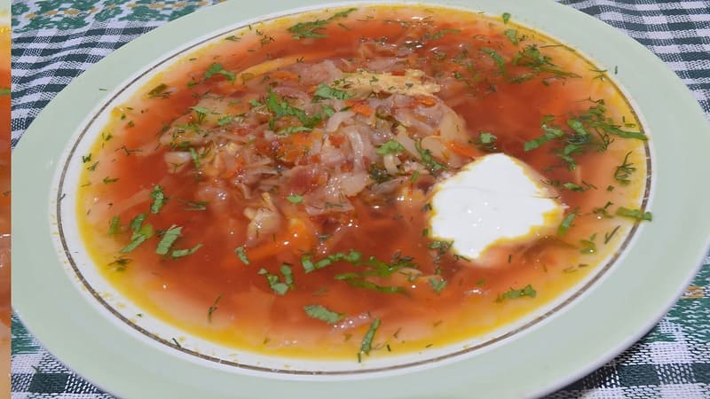 Борщ с кислой капустой и свеклой в тарелке со сметаной и ржаным хлебом