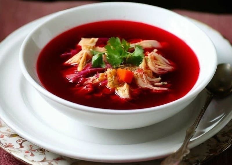 Лёгкий борщ с курицей и свеклой в тарелке со сметаной и зеленью