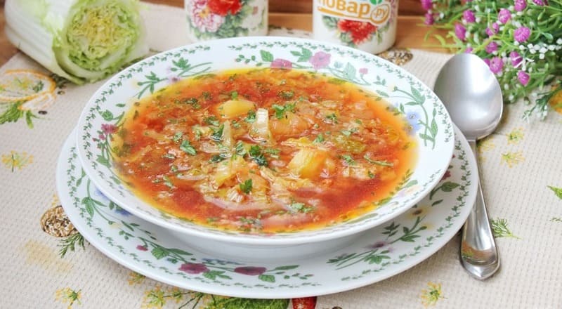 Борщ с пекинской капустой в тарелке со сметаной, зеленью и гренками