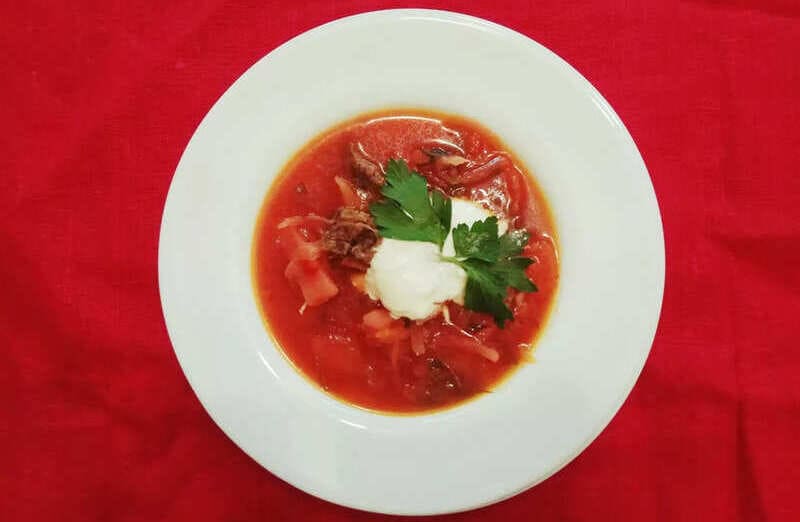Наваристый кубанский борщ с мясом и зеленью в глубокой тарелке