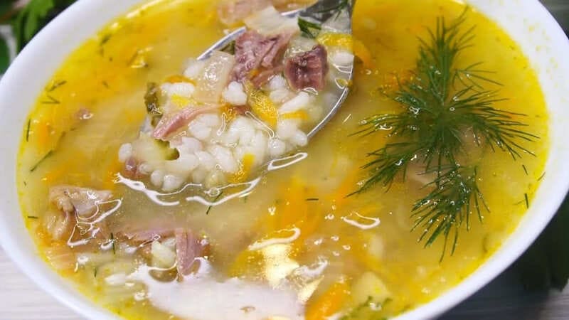 Рассольник с тушенкой и рисом в тарелке