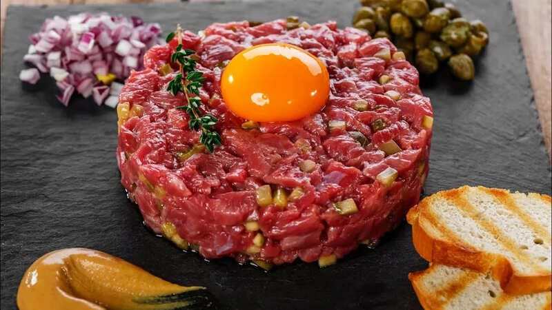 Аутентичный татарский бифштекс с яичными желтками, подается с гренками и маринованными огурчиками